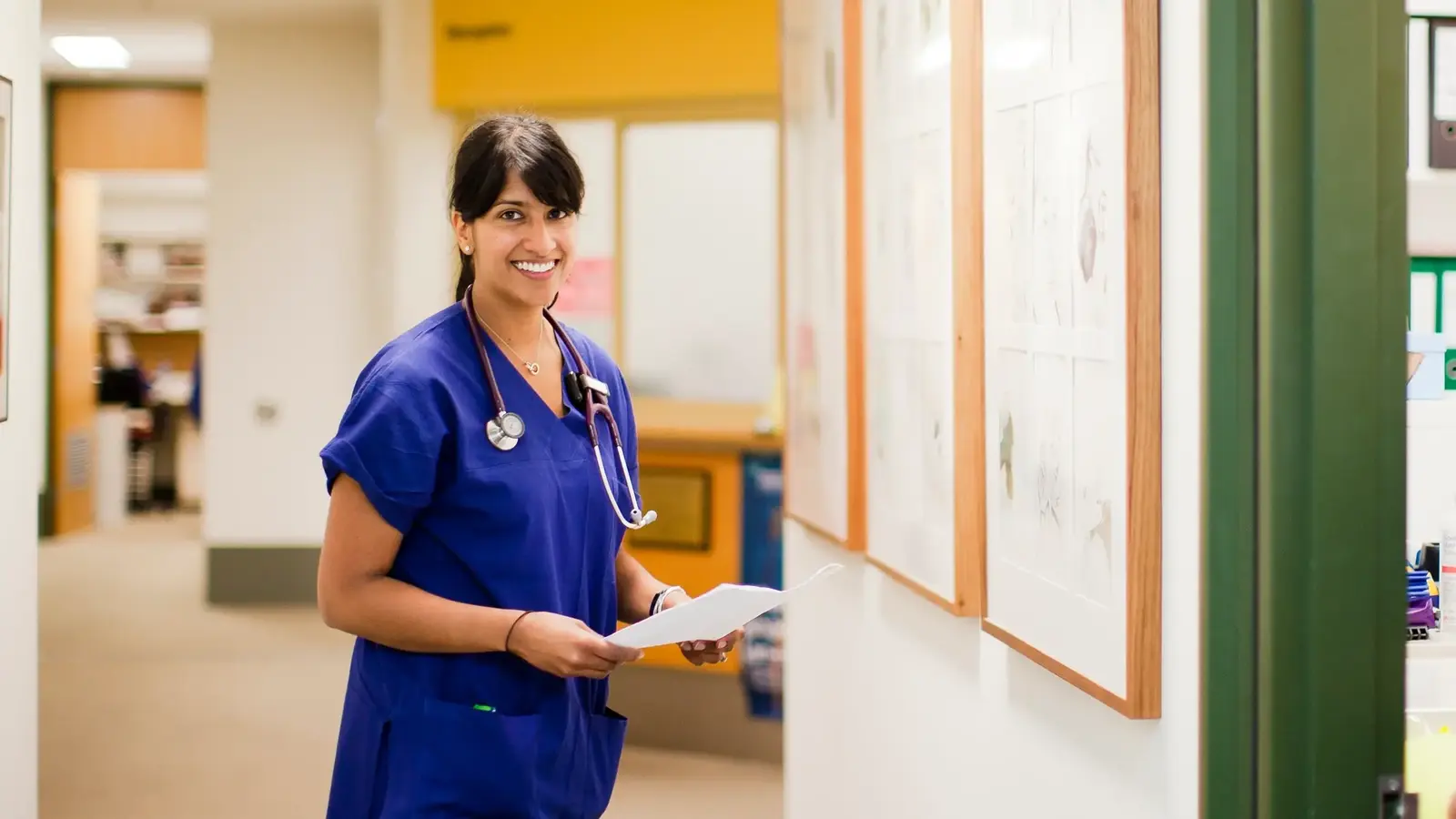 Doctor with stethoscope around neck holding piece of paper and smiling