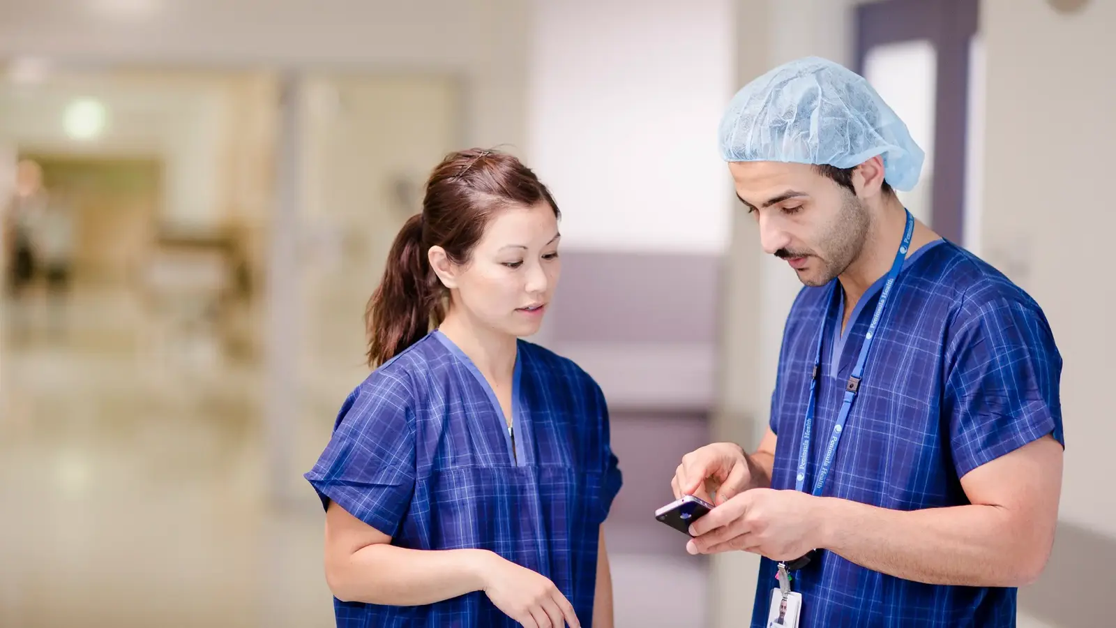 Two people in scrubs looking at phone