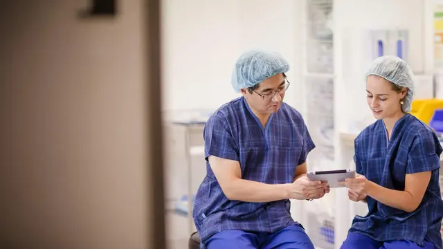 Photo of two doctors sitting together reading a document