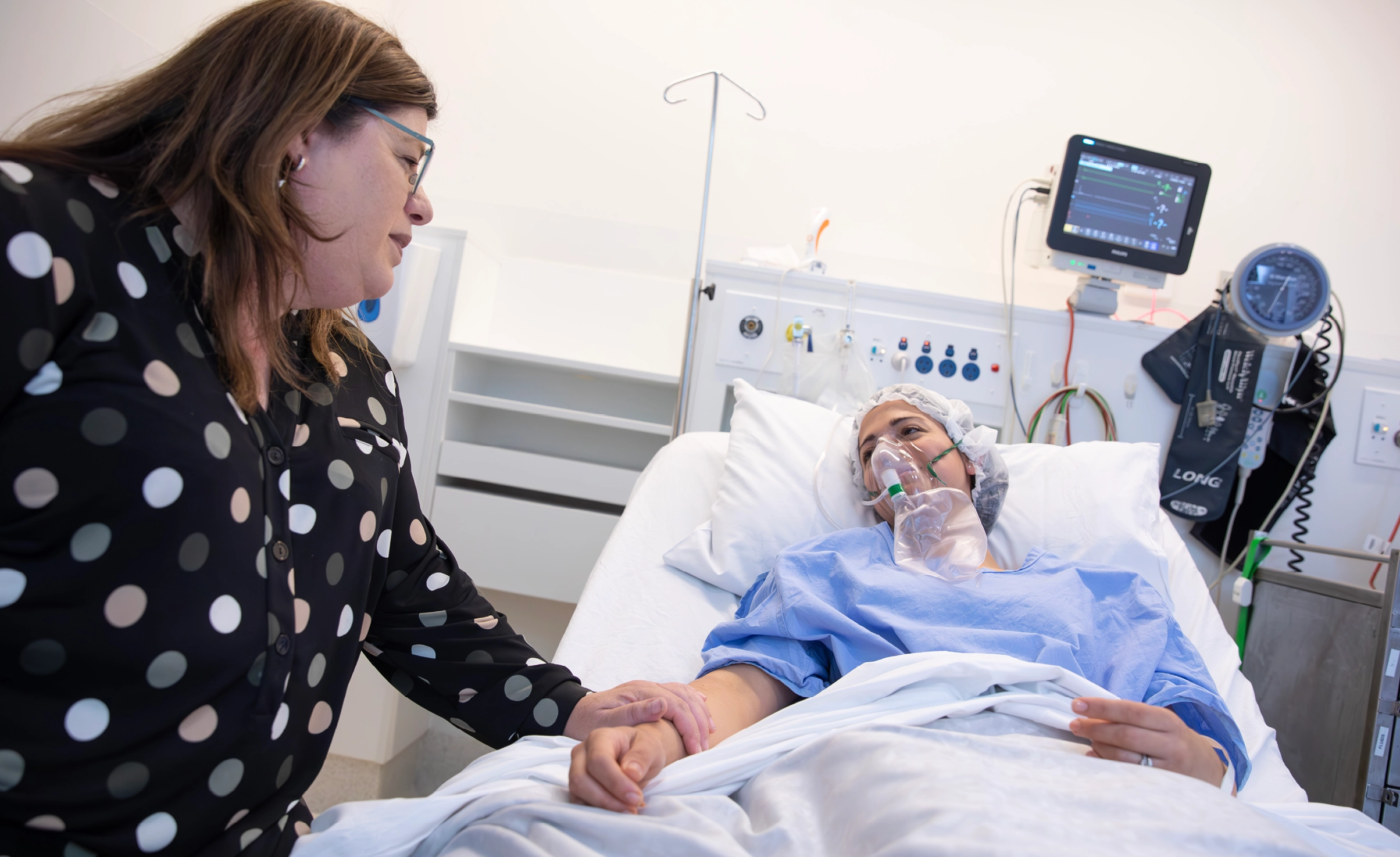 Person comforting patient in hospital bed