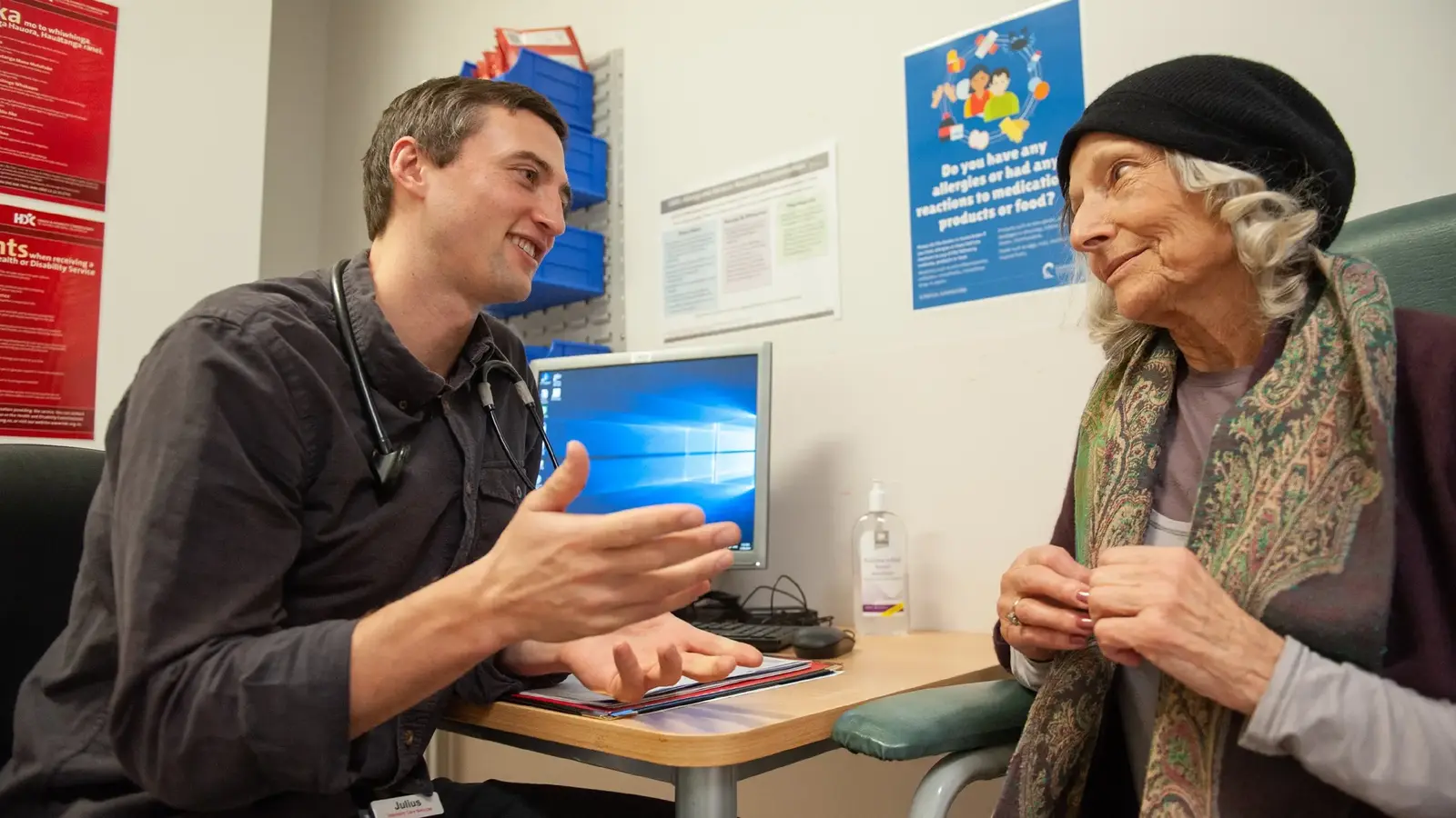 Patient and doctor in consulting room talking to each other in front of computer