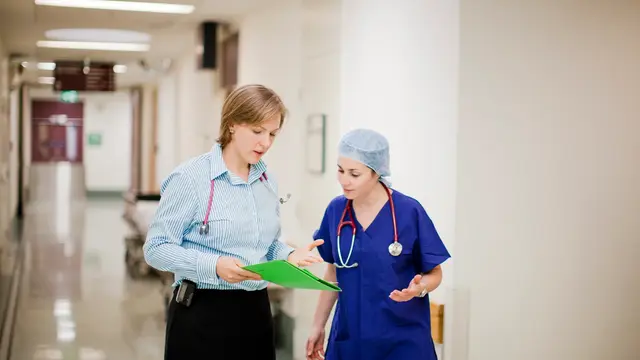 A senior female doctor discusses a chart with a junior doctor