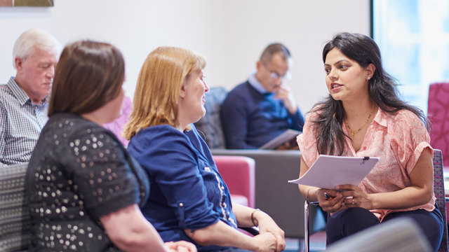 A clinician talking to two people in a clinic waiting room