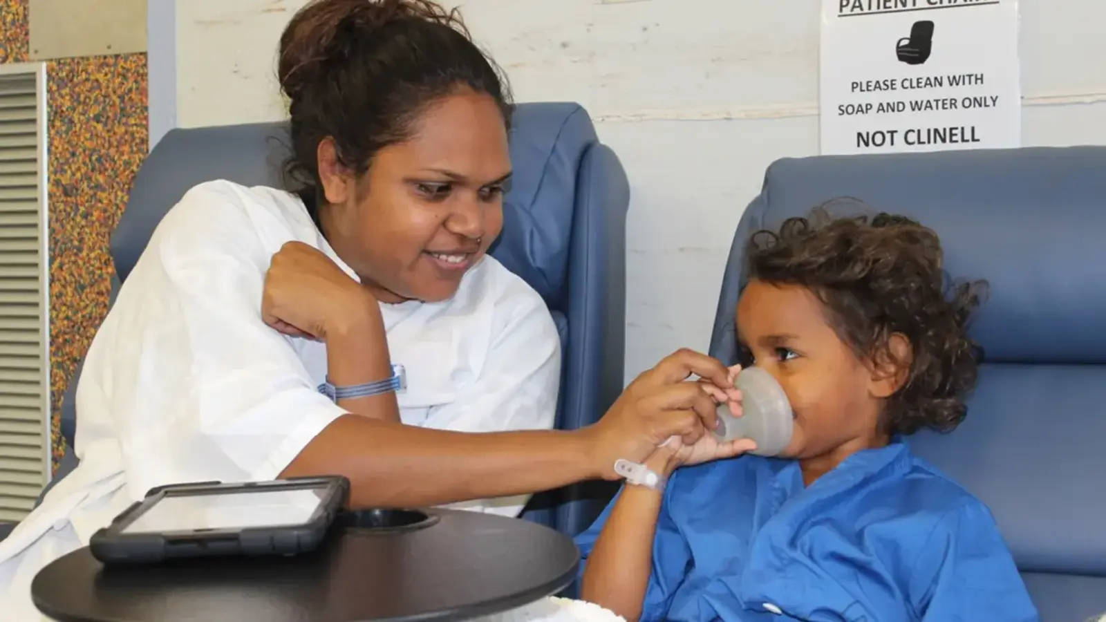 Aboriginal mother placing mask on her child's mouth and nose