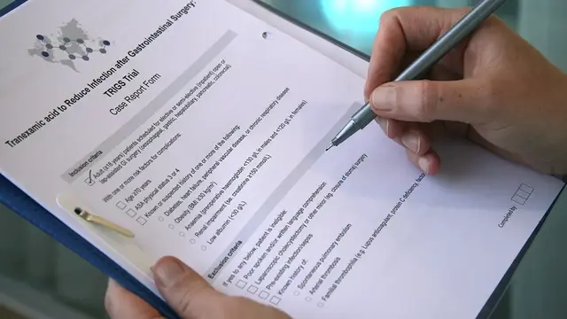 A close-up of a researcher completing a case report form for the TRIGS trial on tranexamic acid in gastrointestinal surgery.