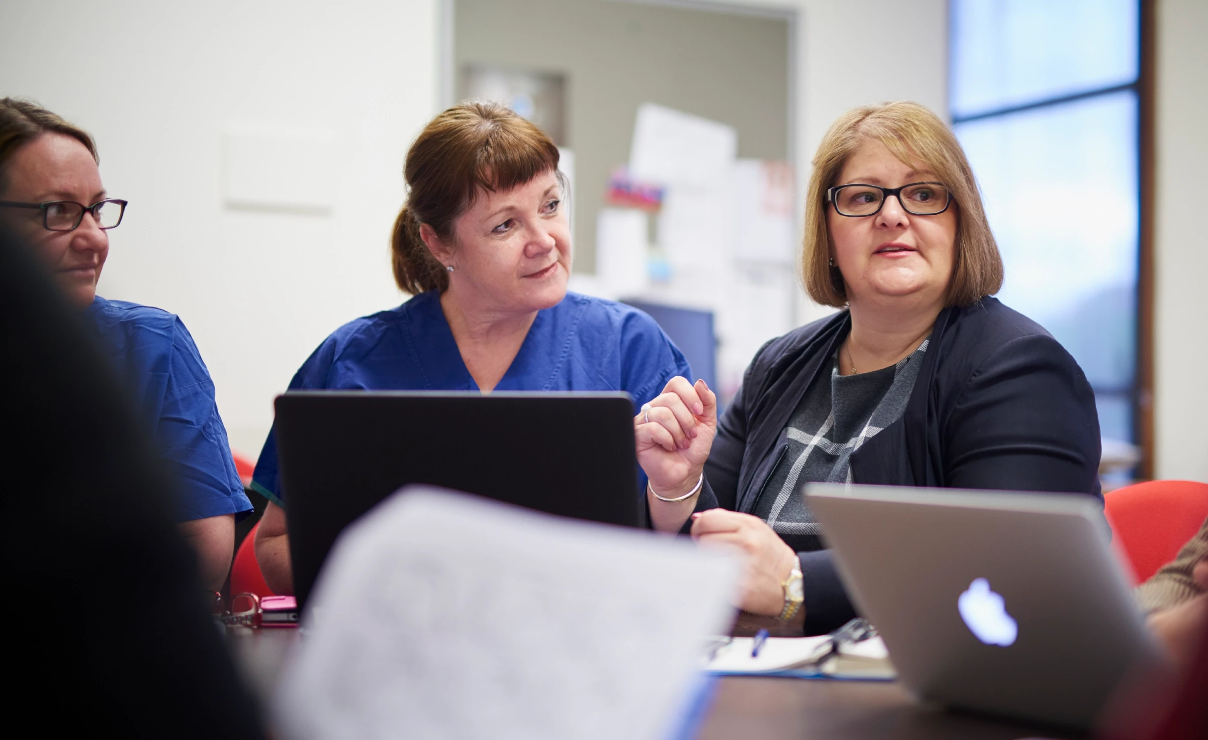 Female doctors talking around a computer