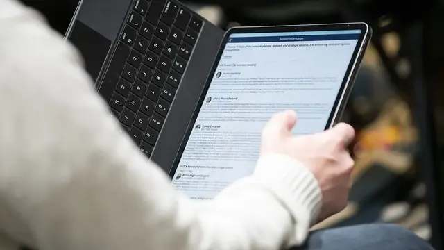 A person using a tablet with a keyboard reading a professional document.