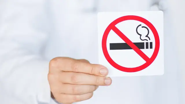 Man holding a 'no smoking' sign