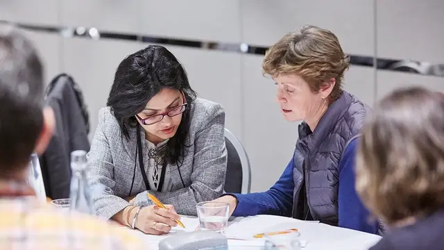 Two professionals discussing a document at a round table. 