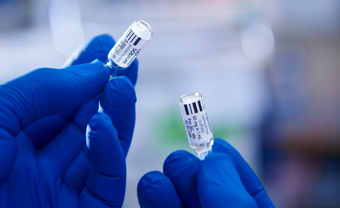 Gloved hands holding up two drug vials